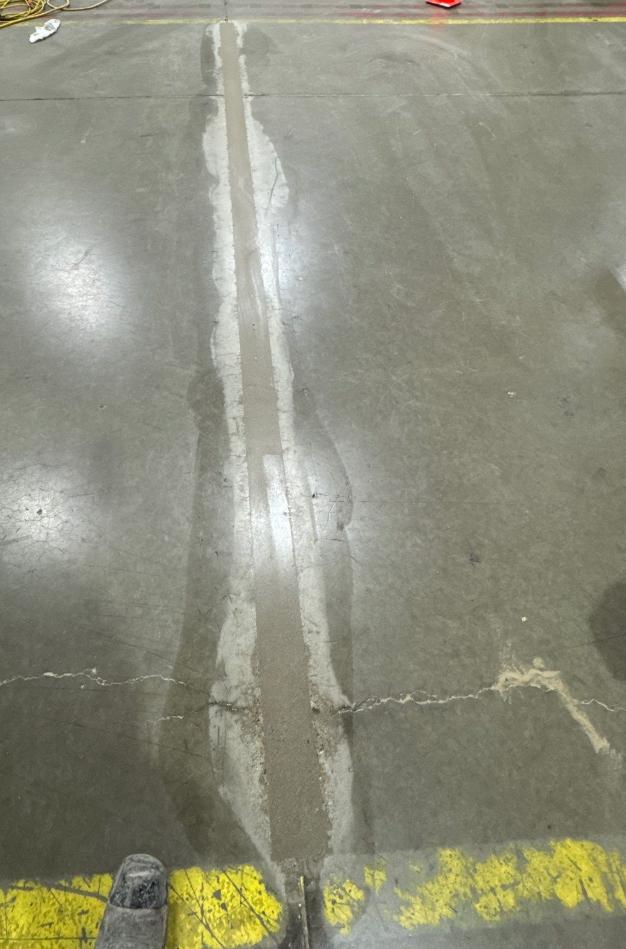Industrial concrete joint repair Repaired concrete floor joint crossing a yellow traffic marking
