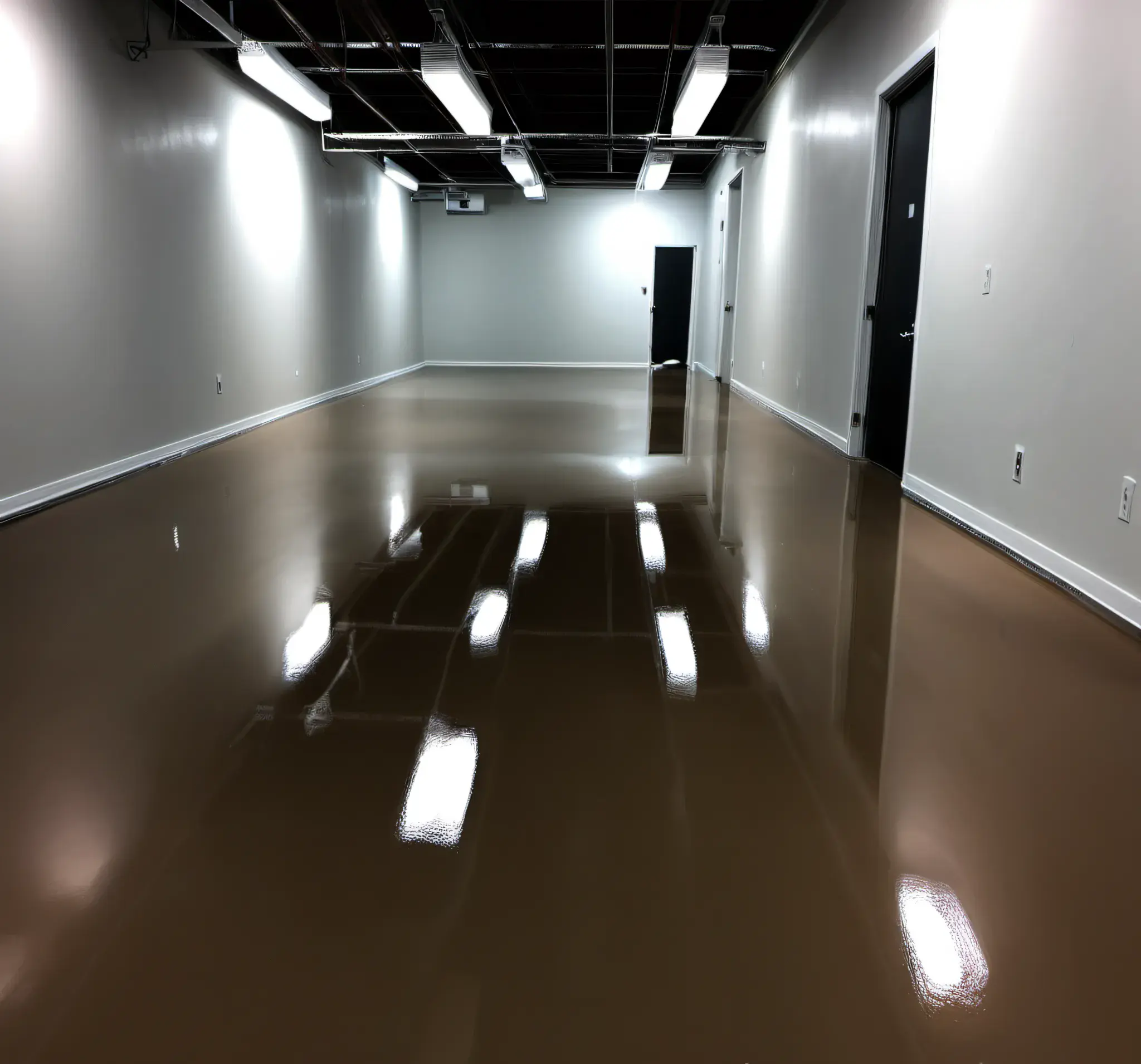 Epoxy, sealed, concrete flooring, with a slight brown tint, set in a small interior room space, with the floors, reflecting the overhead lighting